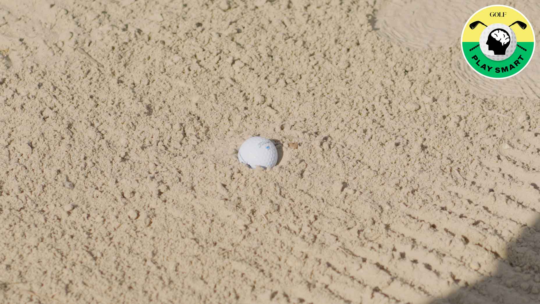 golf ball buried in sand in bunker