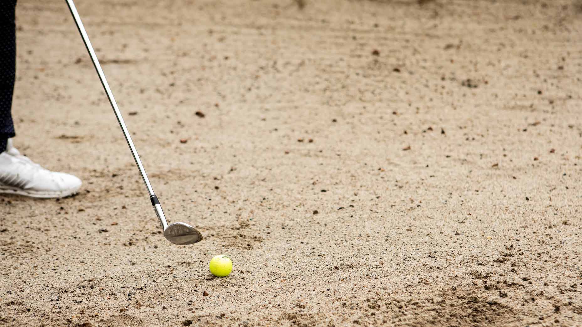 Golfer hitting of firm bunker lie