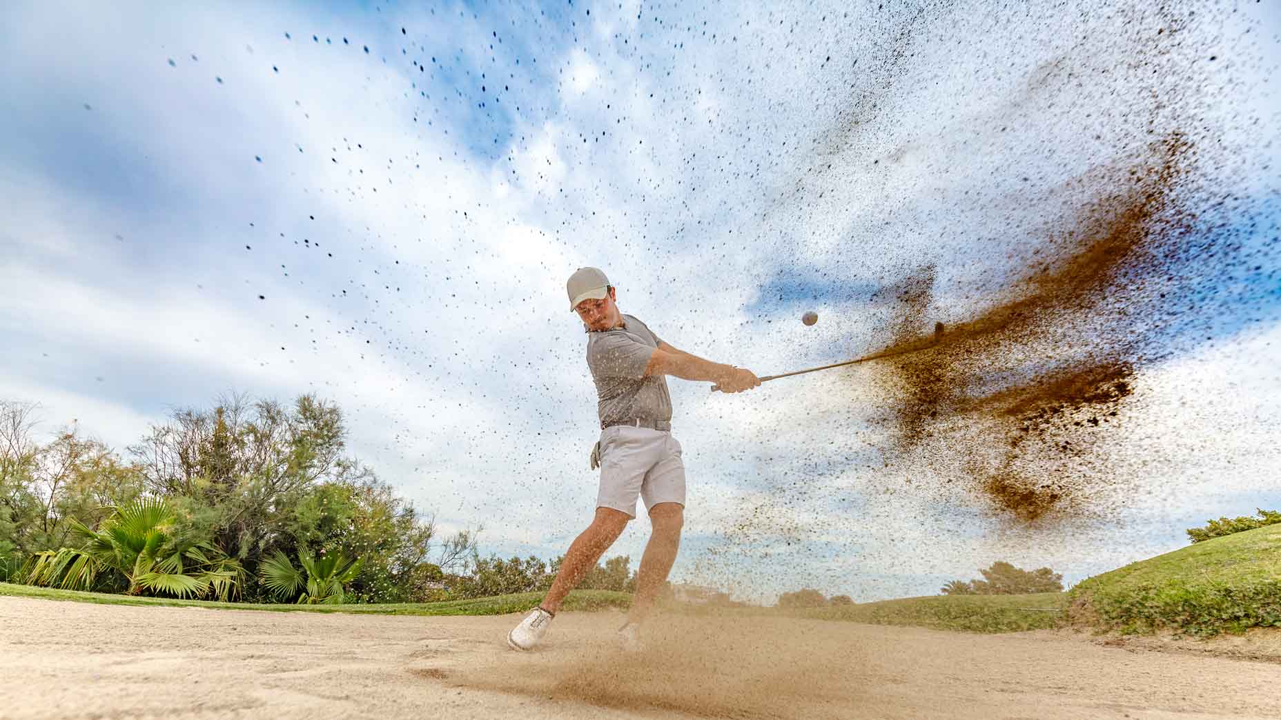 Golfer hitting out of fairway bunker
